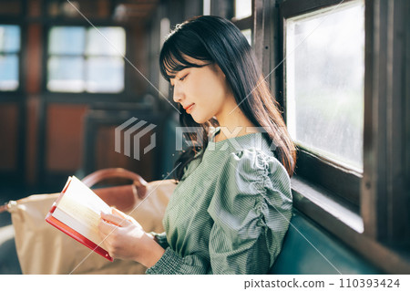 Woman reading a book by train 110393424