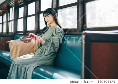 A woman reading a book by train 110393425