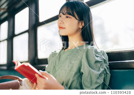 Woman reading a book by train 110393428