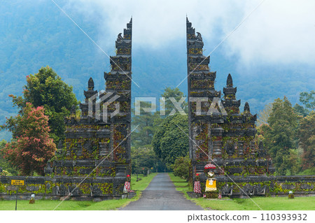 Balinese traditional gate against the background of mountains with clouds on the popular tourist island of Bali. Balinese traditional gate against the background of mountains with clouds on the popular tourist island of Bali. 110393932
