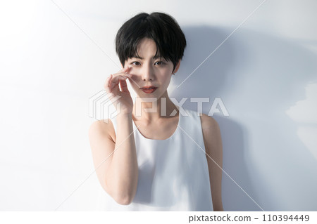 Bust up of a woman with short black hair looking down with an anxious expression 110394449