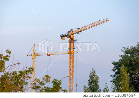 Construction crane stands tall and poised atop a power line in the midst of a bustling city. Construction crane stands tall and poised atop a power line in the midst of a bustling city. 110394584