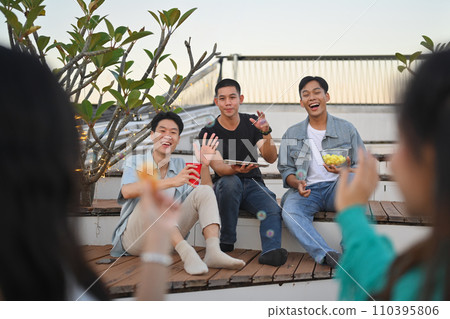 Happy young people gathered together having fun enjoy chill at outdoor rooftop party with drinks. Happy young people gathered together having fun enjoy chill at outdoor rooftop party with drinks. 110395806