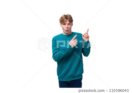 handsome red-haired young man in a blue sweater points his hands up 110396043