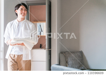 A man carrying laundry bath towels/A man doing housework 110396609