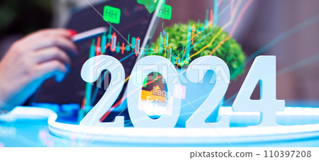 Businessman working at an office desk with a laptop, smartphone and 2024 plant. Forex chart. Double exposure. 110397208