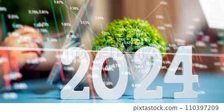 Businessman working at an office desk with a laptop, smartphone and 2024 plant. Forex chart. Double exposure. Businessman working at an office desk with a laptop, smartphone and 2024 plant. Forex chart. Double exposure. 110397209