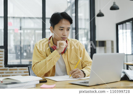 Young collage student using computer and mobile device studying online... Young collage student using computer and mobile device studying online... 110399728