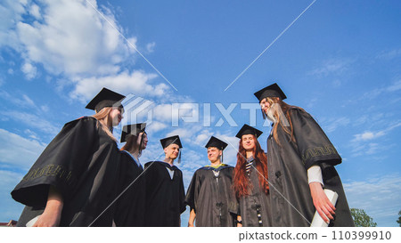Graduating students stand in a semicircle on a sunny summer afternoon. 110399910