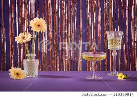 A pot of flowers decorated on purple table with wine glasses. Front view. Empty space in the middle for product promotion. Concept of holiday party 110399914