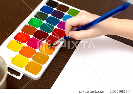 A child draws leafs on a tree. Ideas for drawing with finger paints. Finger painting for kids on white background. Little girl painting by finger hand paint color. Children development concept 110399924
