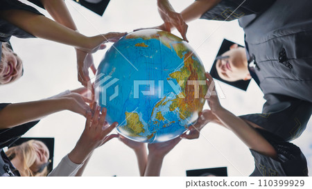 The concept of a world without war. College graduates holding a geographical globe of the world. The concept of a world without war. College graduates holding a geographical globe of the world. 110399929