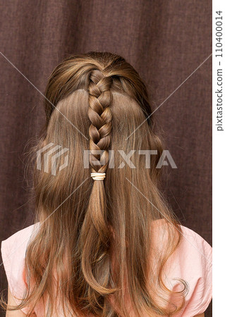 Close-up of a girl's hairstyle with a lush braid, view from the back. Hair styling is done with hairpins and an elastic band. Only the back of the head with a haircut Close-up of a girl's hairstyle with a lush braid, view from the back. Hair styling is done with hairpins and an elastic band. Only the back of the head with a haircut 110400014