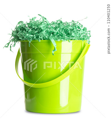 Paper Easter grass in a green plastic bucket. Vibrant colored and crinkled gift basket shred for filling and decoration, stuffed into the bucket, in the form of a nest. Close-up, front view. Photo. Paper Easter grass in a green plastic bucket. Vibrant colored and crinkled gift basket shred for filling and decoration, stuffed into the bucket, in the form of a nest. Close-up, front view. Photo. 110401250