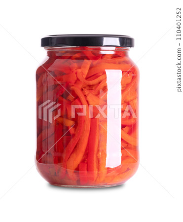 Red bell peppers, pickled in a glass jar. Sweet pepper slices, pasteurized and preserved in a brine of vinegar and salt. Used as salad or side dish. Close-up front view on white background. Photo. 110401252