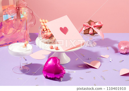 Cards, gift bags, heart balloons, paper hearts, chocolates, wafer rolls and candy balls are displayed on a pastel purple background. Valentine's Day party table. 110401910