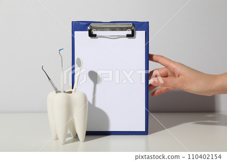 A glass in the shape of a tooth with dental tools. 110402154