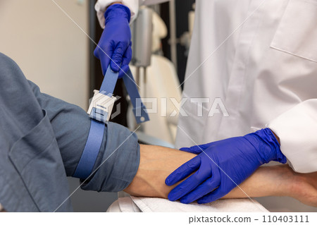Unrecognizable man preparing for insertion of drip in clinic. Unrecognizable man preparing for insertion of drip in clinic. 110403111