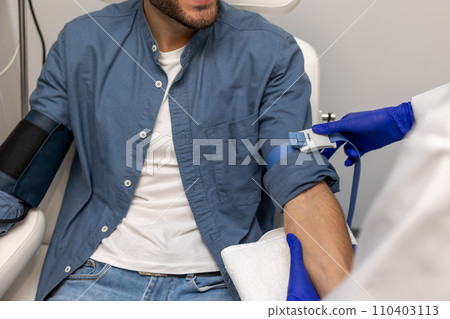 Unrecognizable man preparing for insertion of drip in clinic. Unrecognizable man preparing for insertion of drip in clinic. 110403113