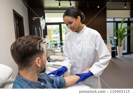 Doctor cosmetologist preparing male client arm for insertion of drip. 110403115