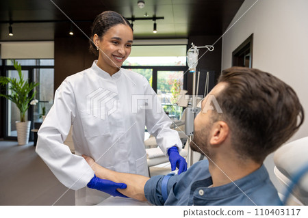 Doctor cosmetologist preparing male client arm for insertion of drip. Doctor cosmetologist preparing male client arm for insertion of drip. 110403117