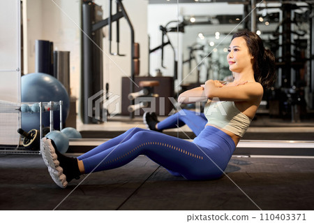 Woman training her abdominal muscles with crunches 110403371