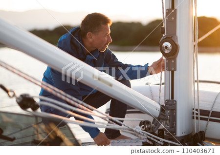 Mature man sailing on the yacht and looking busy 110403671