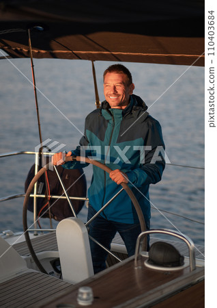 Mature man standing near the steering whell on the yacht 110403684