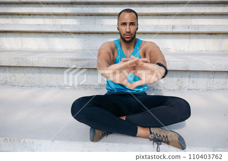 Young man sitting in a lotus pose while exercising Young man sitting in a lotus pose while exercising 110403762