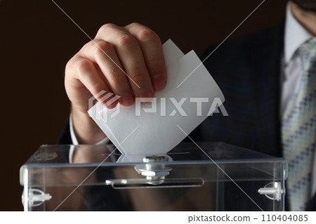 Transparent box and hand with voting paper on brown background, close up 110404085