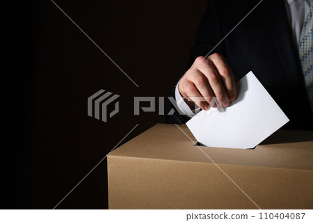 Paper box and hand with voting paper on dark background, space for text Paper box and hand with voting paper on dark background, space for text 110404087
