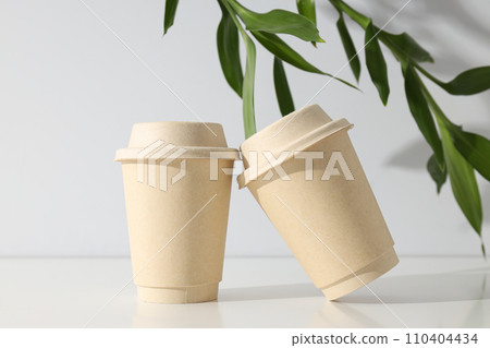Paper cups with lids and green leaves Paper cups with lids and green leaves 110404434