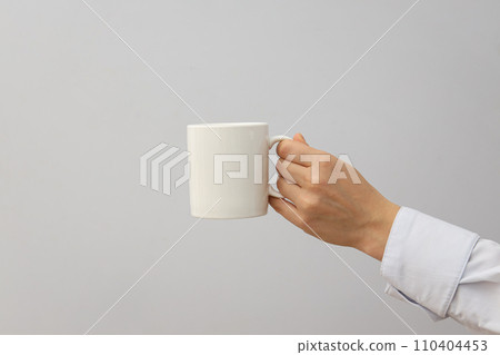 A woman holds a white cup in her hands 110404453