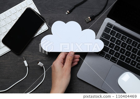 White, paper cloud with various gadgets on a black table background White, paper cloud with various gadgets on a black table background 110404469