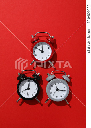 Classic multi-colored alarm clocks with on a red background Classic multi-colored alarm clocks with on a red background 110404653