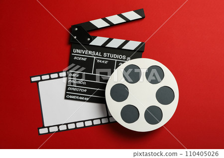 Clapperboard, paper reel and film on red background, top view 110405026