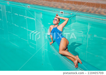 Bikini-clad woman enjoys poolside relaxation. Poolside ambiance. Capturing woman's relaxed time near pool. Bikini-clad woman enjoys poolside relaxation. Poolside ambiance. Capturing woman's relaxed time near pool. 110405709