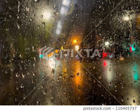 Rain bokeh road lights. Abstract shot of evening city traffic bokeh. Multicolored lights of the evening city and passing cars through a wet rainy window. Rain bokeh road lights. Abstract shot of evening city traffic bokeh. Multicolored lights of the evening city and passing cars through a wet rainy window. 110405737