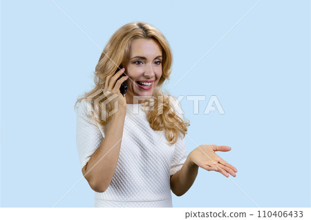Portrait of happy mature blonde talking on the phone. Isolated pastel blue background. 110406433