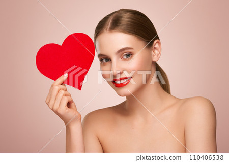 Beautiful woman holding an artificial red heart Beautiful woman holding an artificial red heart 110406538