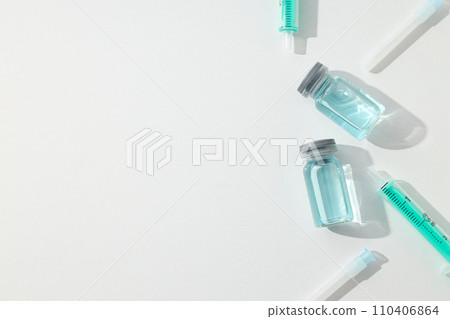 Glass medical bottles with vaccine and syringes on white background, space for text 110406864