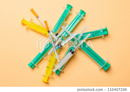 Top view of a heap of syringes and insulin syringes at orange background. Medical injection concept with copy space 110407206