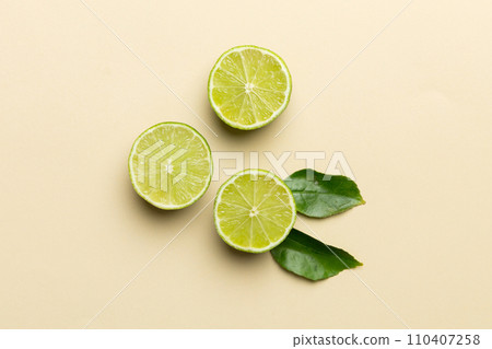 Lime fruits with green leaf and cut in half slice isolated on white background. Top view. Flat lay with copy space Lime fruits with green leaf and cut in half slice isolated on white background. Top view. Flat lay with copy space 110407258