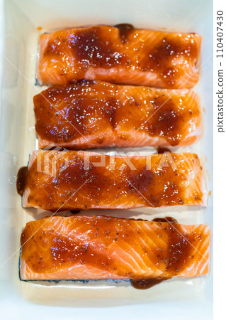 Baking pieces of fresh salmon with teriyaki sauce in an oven-safe ceramic dish. Baking pieces of fresh salmon with teriyaki sauce in an oven-safe ceramic dish. 110407430