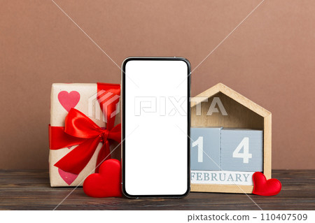 mobile phone with blank screen on colored background with hearts, calendar and gift box, valentine day 14 february concept perspertive view flat lay mobile phone with blank screen on colored background with hearts, calendar and gift box, valentine day 14 february concept perspertive view flat lay 110407509