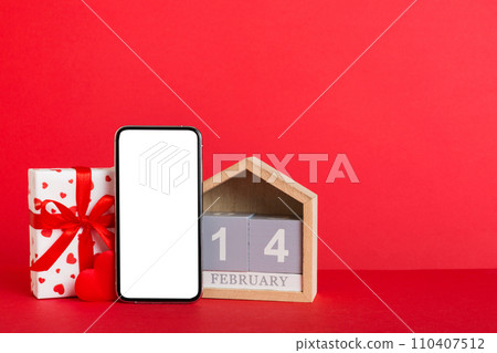 mobile phone with blank screen on colored background with hearts, calendar and gift box, valentine day 14 february concept perspertive view flat lay mobile phone with blank screen on colored background with hearts, calendar and gift box, valentine day 14 february concept perspertive view flat lay 110407512