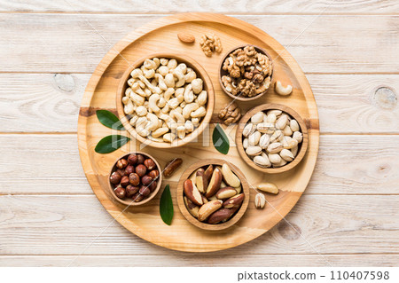 mixed nuts in wooden bowl. Mix of various nuts on colored background. pistachios, cashews, walnuts, hazelnuts, peanuts and brazil nuts mixed nuts in wooden bowl. Mix of various nuts on colored background. pistachios, cashews, walnuts, hazelnuts, peanuts and brazil nuts 110407598