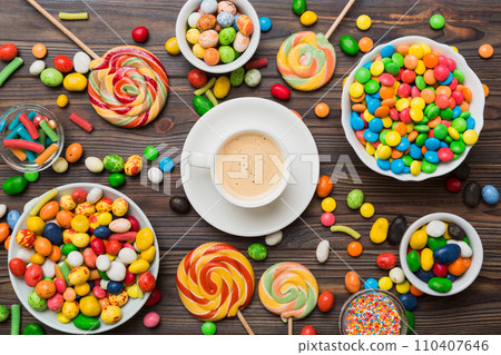 Coffee cup with chocolates and colored candy. Top view on table background with copy space Coffee cup with chocolates and colored candy. Top view on table background with copy space 110407646