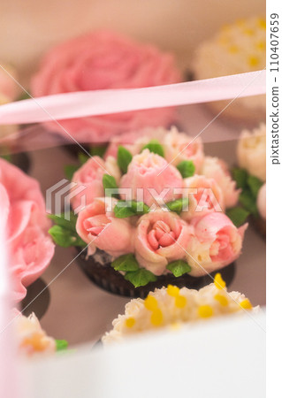 Encased in a pristine white paper cupcake box, each gourmet cupcake is a work of art, adorned with buttercream frosting flowers beautifully designed to resemble vibrant roses and tulips. Encased in a pristine white paper cupcake box, each gourmet cupcake is a work of art, adorned with buttercream frosting flowers beautifully designed to resemble vibrant roses and tulips. 110407659