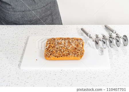 Scoring pumpkin spice fudge using a wheel dough cutter for cutting into small pieces. 110407701